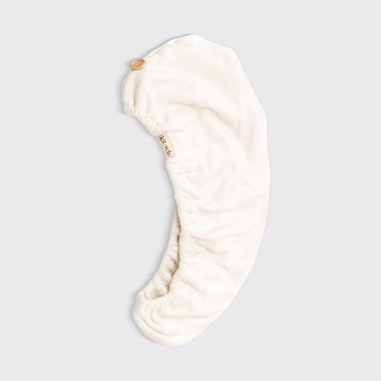 Cream-colored microfiber hair towel wrap with button closure; eco-friendly. Available in S/M and L/XL. Quick-drying care.