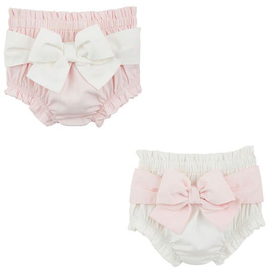 Two Cotton Poplin Diaper Covers: Baby bloomers with contrast bows. Top: pale pink with white bow; Bottom: white with pale pink bow. Ruffled elastic waistbands and leg openings. Available sizes: Newborn, 0-3M, 3-6M, 6-12M.