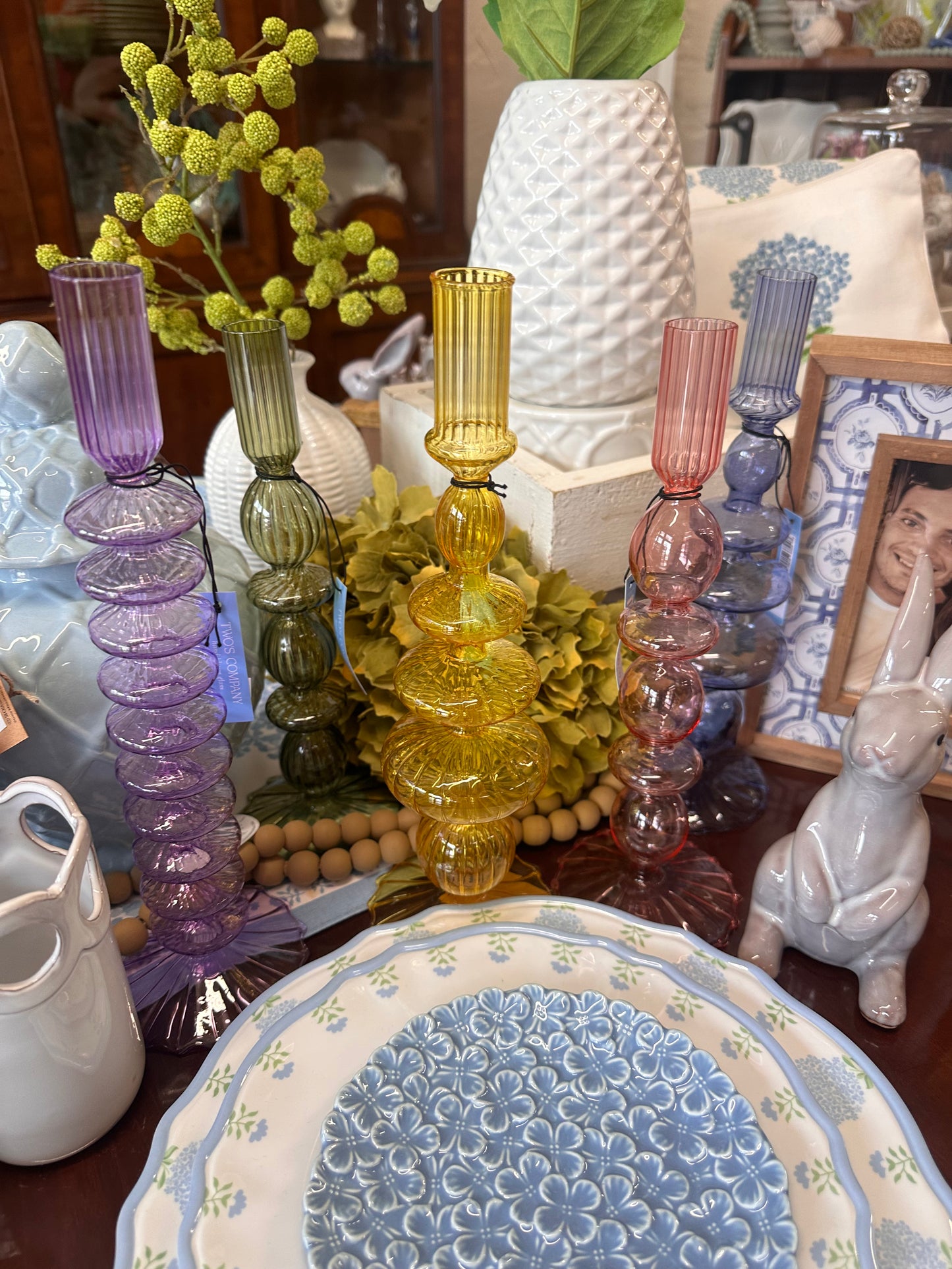 Five colored glass candleholders in purple, green, yellow, pink, and red. Available in small and large sizes.