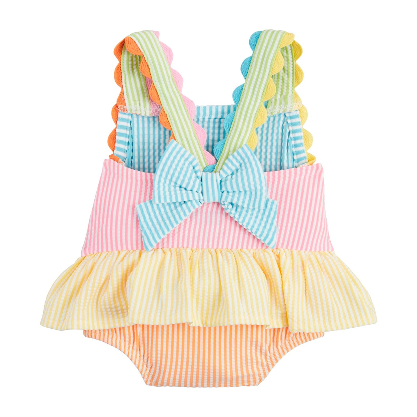 A vibrant baby dress with pink, blue, yellow, and orange stripes, featuring scalloped crossed straps, a large back bow, and a ruffled skirt. Available sizes: 3M, 6M, 9M, 12M.