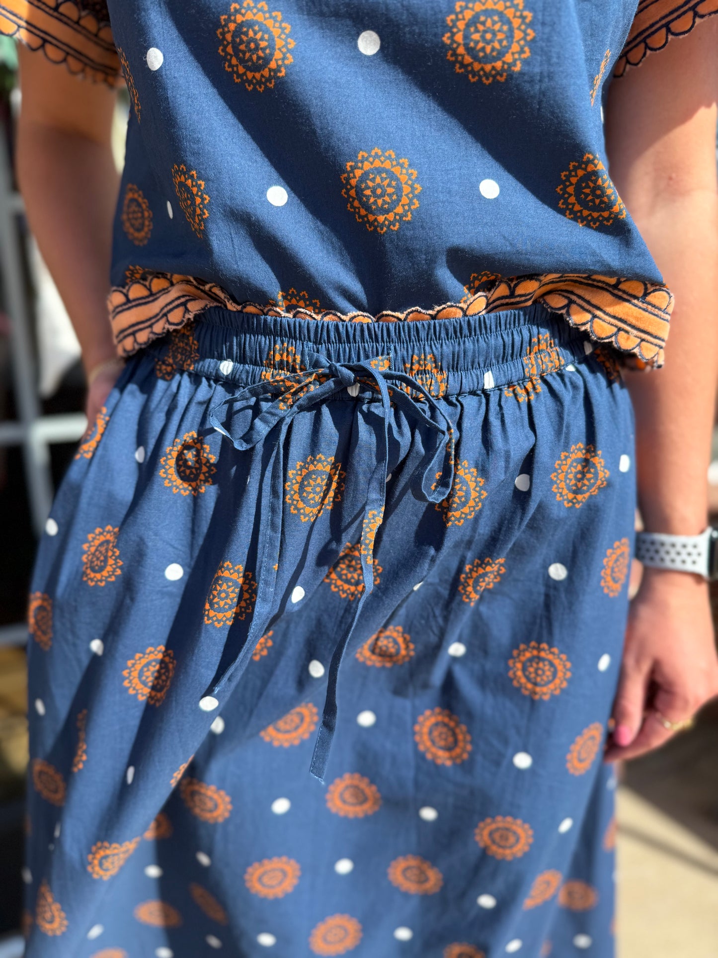 Auburn Medallion Skirt Set: blue two-piece with orange medallion patterns, white polka dots, and a cinched drawstring waist. Available in sizes XS–XL.