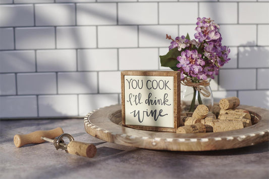 The Mini "You Cook I'll Drink Wine" Box Sign is a decorative piece expressing lighthearted wine appreciation. Size: Approximately 3" x 4".