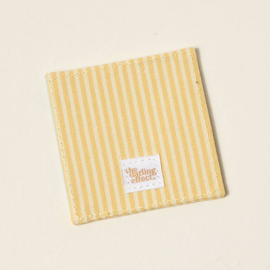 Yellow-and-white striped fabric bookmark, stitched edges, gold "the smiling effect" label. Sizes available.