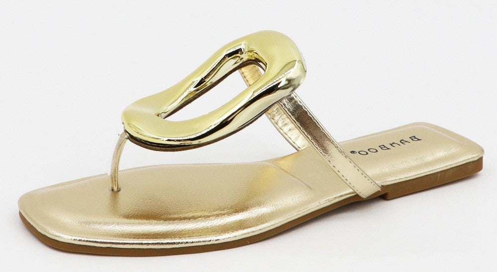 Gold metallic flat sandal with square toe, thin thong strap, large glossy gold link on upper, cushioned insole, and tan sole. Available in sizes 5-11.
