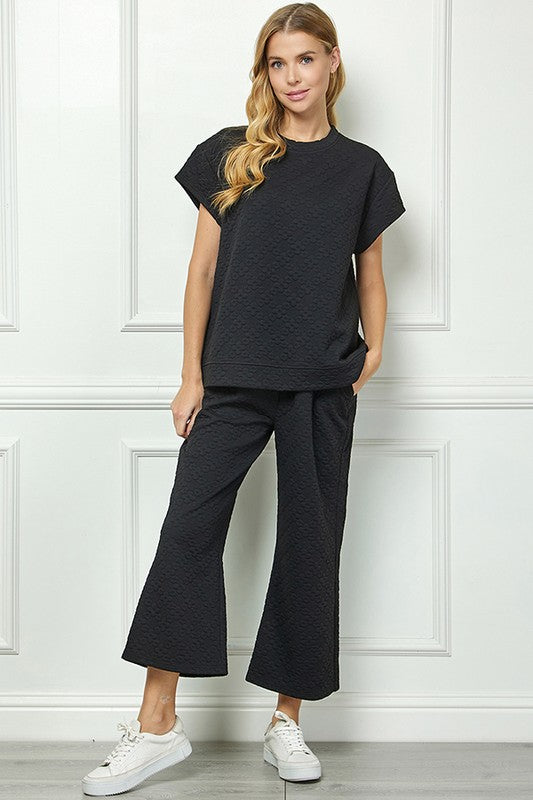 Flower Textured Black Set: loose short-sleeve top and wide-leg pants. Available in sizes XS–XL.