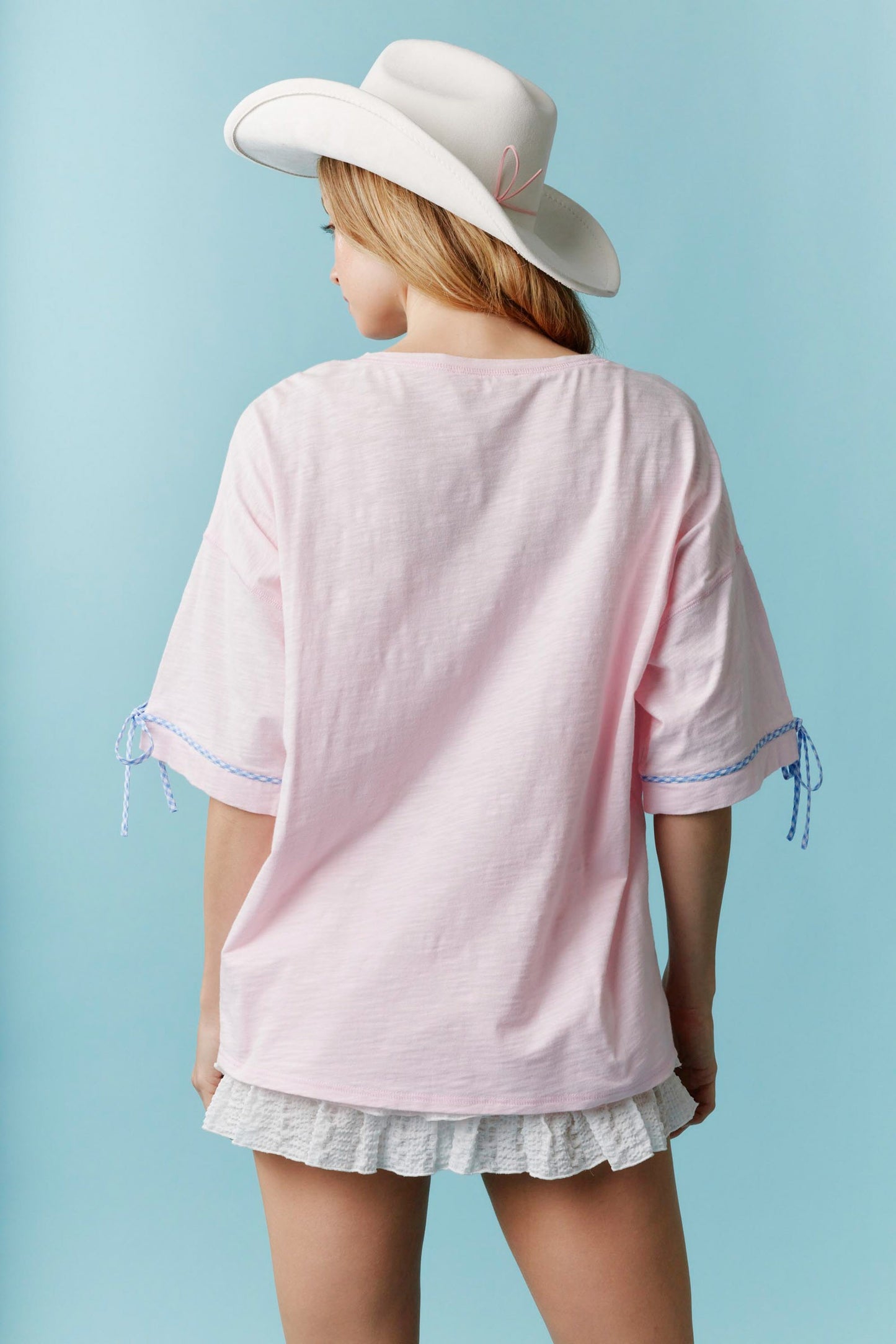 Americana Gingham Bow T-Shirt: Light pink fabric with gingham bow details on the sleeves. Available in sizes XS–XXL.