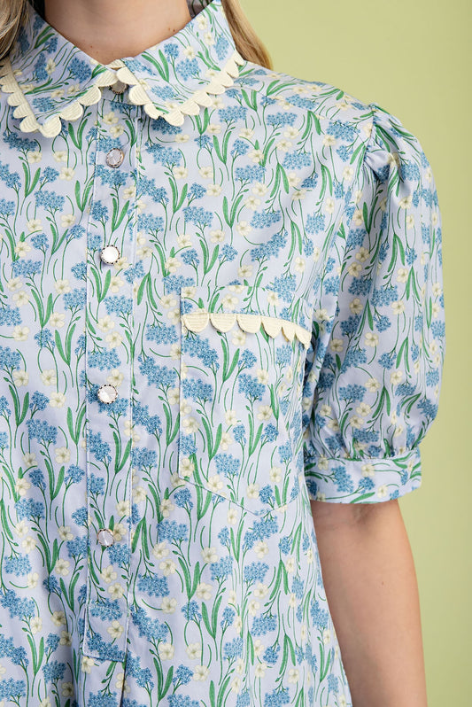 Mia Floral Print Mini Dress in light blue 100% cotton with green and white floral pattern, lace-trimmed collar, and puffed short sleeves. Available in sizes XS–XL.