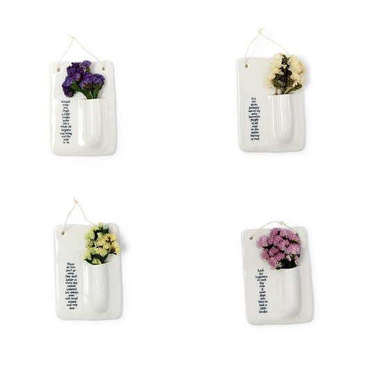 Set of four small white porcelain wall vases with dried flowers and printed messages. Available in mini size.