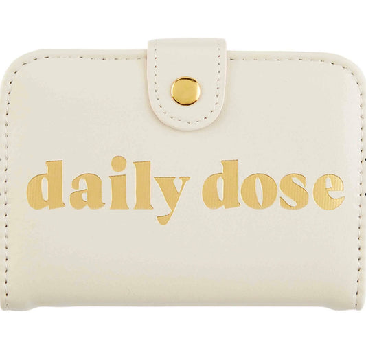 Cream wallet-style pill case with snap closure, "daily dose" in gold. Available in small and large sizes.