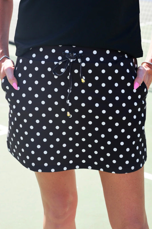 Dot Your Day Performance Skort—black with polka dots, drawstring waist, pockets. Available in sizes XS–XL.