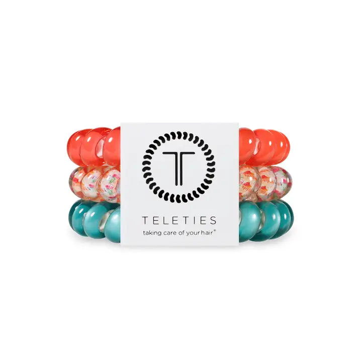 Three TELETIES Hair Ties—coral, multicolor confetti, teal—white logo label. Available in small and large sizes.