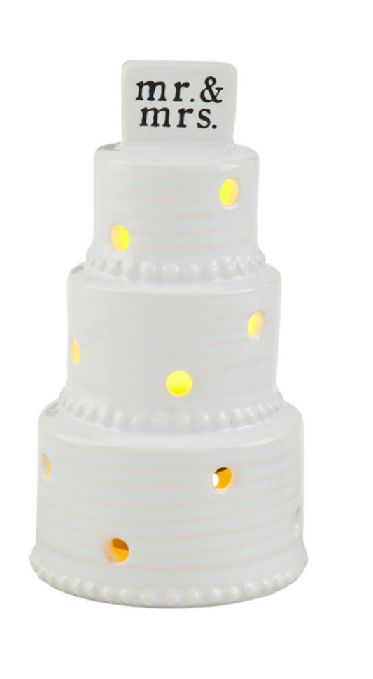 Oh this is a wedding cake lot up and sound sitter it's a three tier cake that has several holes were light shines through topped by Mr. and Mrs. and black lettering the rest of the cake is made from ceramic