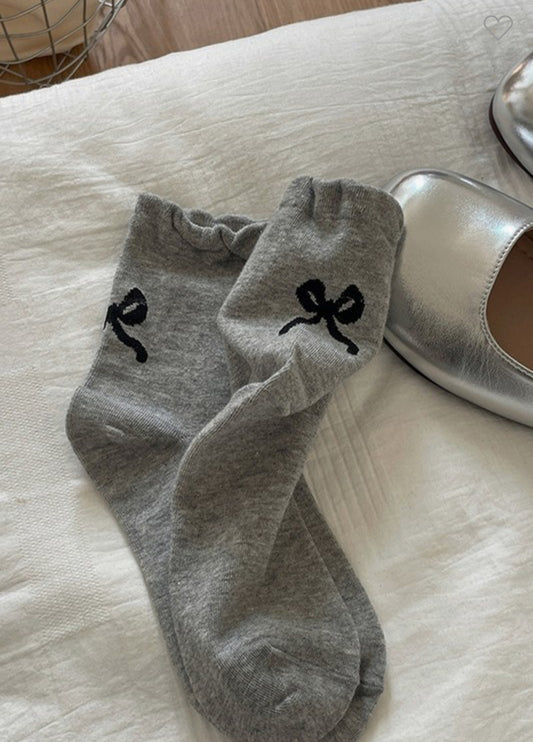 This product is a pair of grey mid-calf socks featuring cute frowning face designs. The socks are only available in one size designed to fit most adults. The product does not include a white bedsheet or metallic silver shoe.