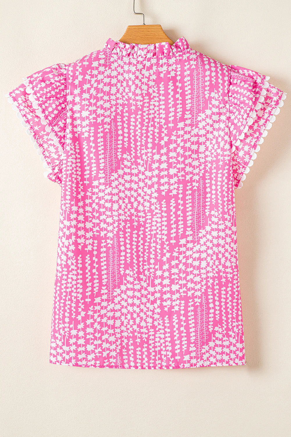 Pink blouse with abstract print, ric rac trim, notch V-neck, pompom-trimmed flutter sleeves. Available in sizes XS-XL.
