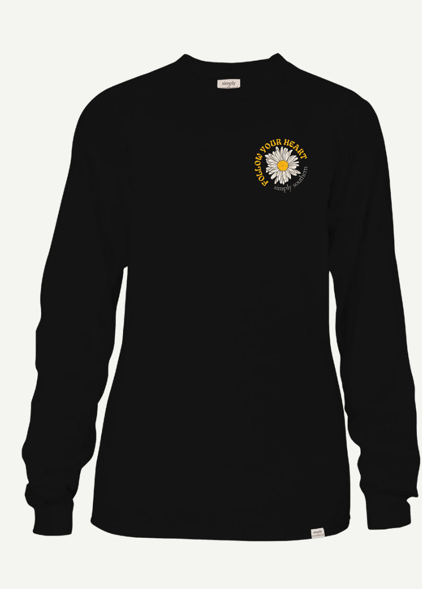 A long-sleeved black Herd Comet Tshirt with a small sunflower design and the phrase "FOLLOW YOUR HEART NOT THE HERD" printed in white on the upper left chest area.