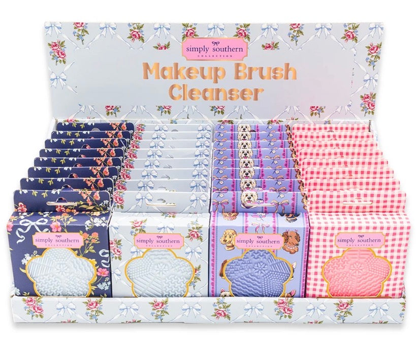 Makeup Brush Cleanser by Simply Southern in compact sizes, available in blue floral, navy floral, purple dog print, and pink gingham patterns. Each has a decorated package with a textured silicone cleaning pad on the front.
