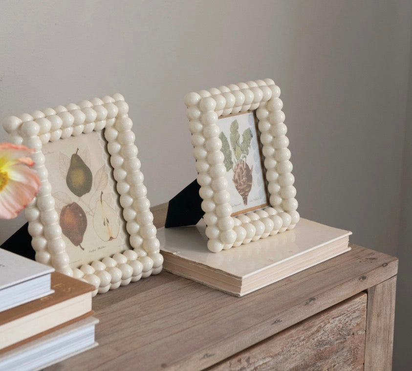 Two resin and glass ball photo frames with beaded cream borders; available in two sizes.