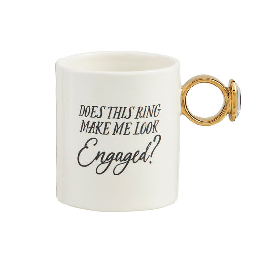The Bridal Ring Mug: Hand-painted ceramic with a large, gold ring-shaped handle. Features "DOES THIS RING MAKE ME LOOK Engaged?" in stylized black font. Sizes available: Standard mug size.