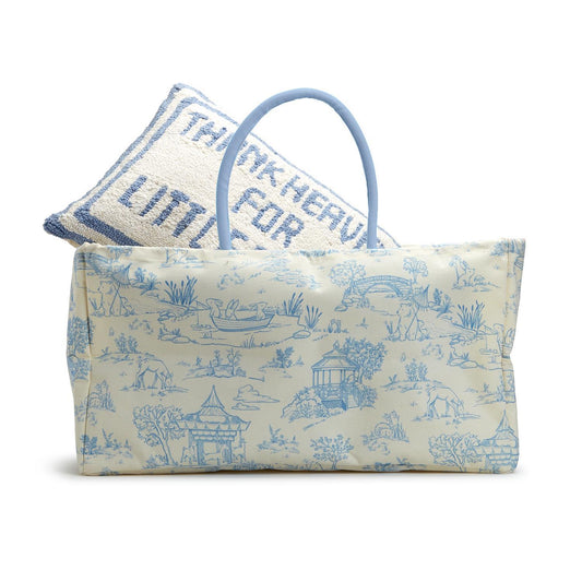 Large, rectangular tote bag with light blue handles; features a pastoral scene pattern in blue on a light background. Contains a white knitted pillow with blue trim and text "THANK HEAVEN LITTLE FOR G." Ideal for nursery storage. Available sizes: Large.