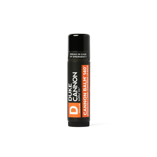 Black tube of Cannon Balm Lip Balm 140° SPF 30 by Duke Cannon with orange and white label; available in standard size.