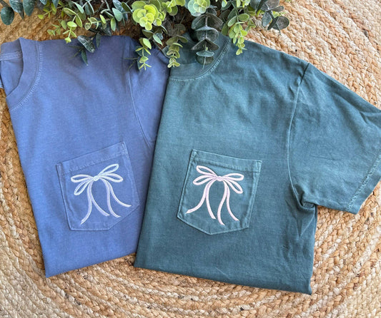 Unisex White Bow Comfort Color T-Shirts in washed blue and green, white bow embroidered on pocket. Available in S-XL.