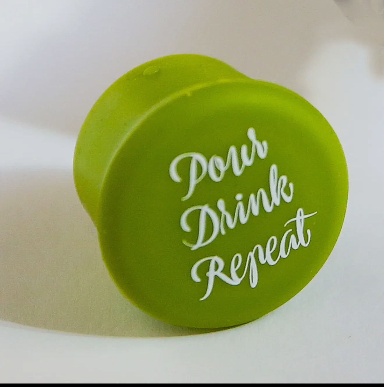 Green cap reads "Pour Drink Repeat" in white cursive; reseals wine bottles. Available in standard and large sizes.