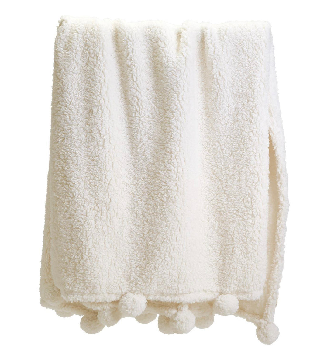 Ultra-soft sherpa throw in a neutral tone with pom-poms on the edge, neatly folded. Available in 50"x60" and 60"x70".