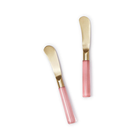 The Pink Blush Set of Two Spreaders features sleek, golden stainless steel blades and shiny pink acrylic handles—perfect for entertaining. Available in one size.