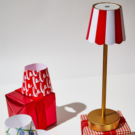 The LED Cordless Table Lamp with Scalloped Edge Shade features a golden base and a red and white striped shade. Includes touch button functionality and rechargeable battery. Sizes available: Small, Medium, Large.