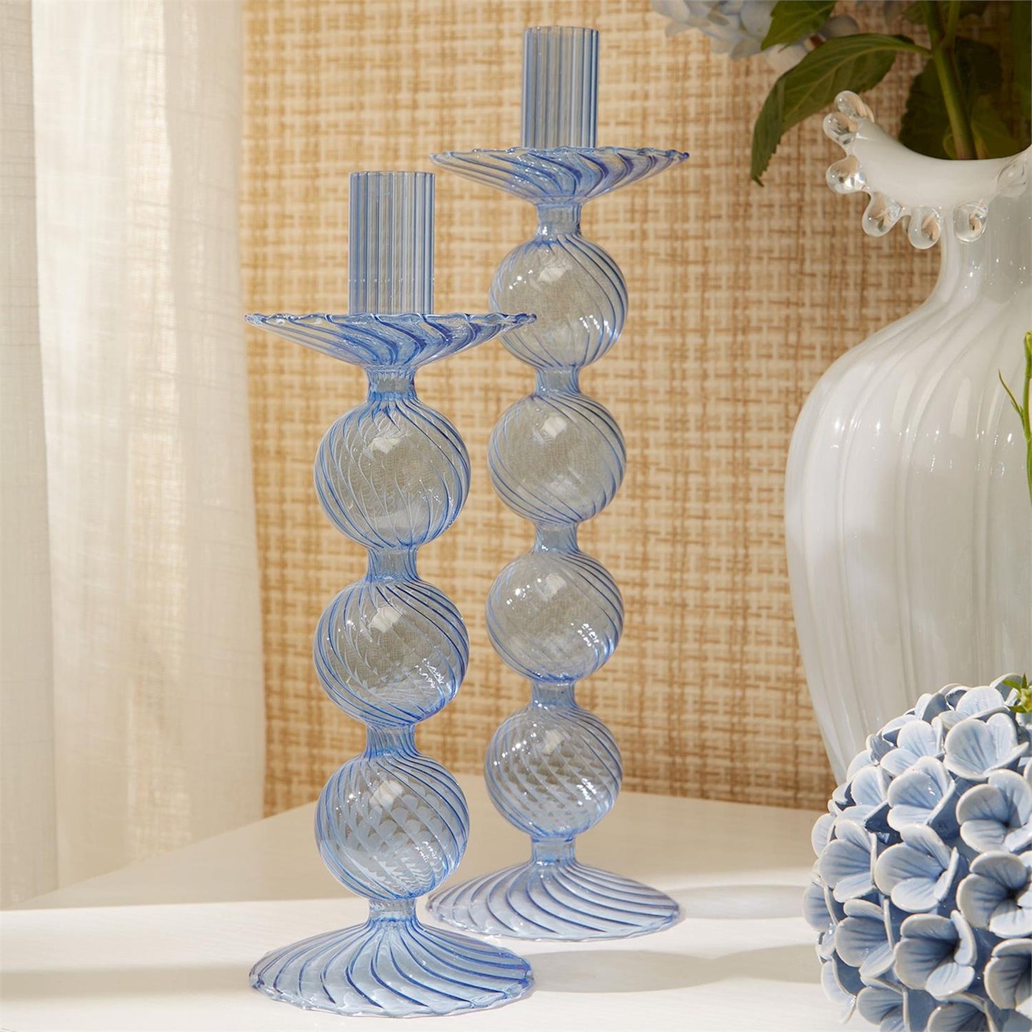Two blue hand-blown glass taper candlesticks featuring spherical designs. Sizes available: Not specified.
