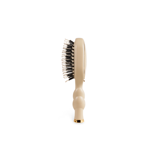 The Mini Boar Brush | Tan has a contoured handle with black and white bristles. Available in mini size.