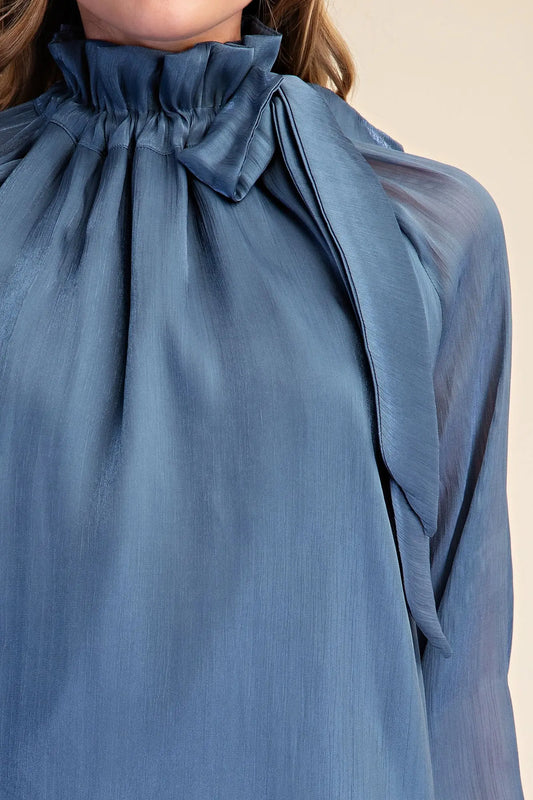 Ruffle Neck Adjustable Tie Long Sleeve Blouse in shiny light blue chiffon with high ruffled neckline, side adjustable tie, long sleeves, and loose fit. Available in sizes XS–XL.