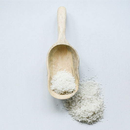 Hand carved mango wood scoop filled with powder. Available in small, medium, and large sizes.