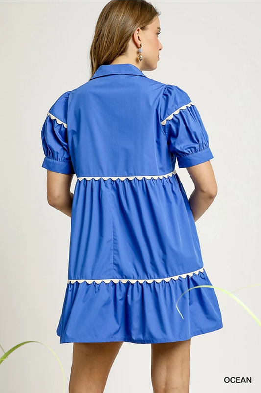 Nellie Azure Ric Rac Dress: bright blue babydoll style, puffed sleeves, white ruffle trim. Available in XS–XL.