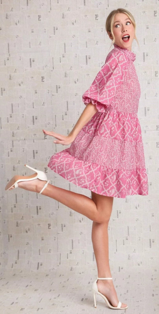 This hundred percent cotton dress is pink. It has tears down the front with a pattern Paisley and his light, pink darker, pink light, pink and darker pink down the front. It has a elastic 3/4 sleeves and a ruffled collar.