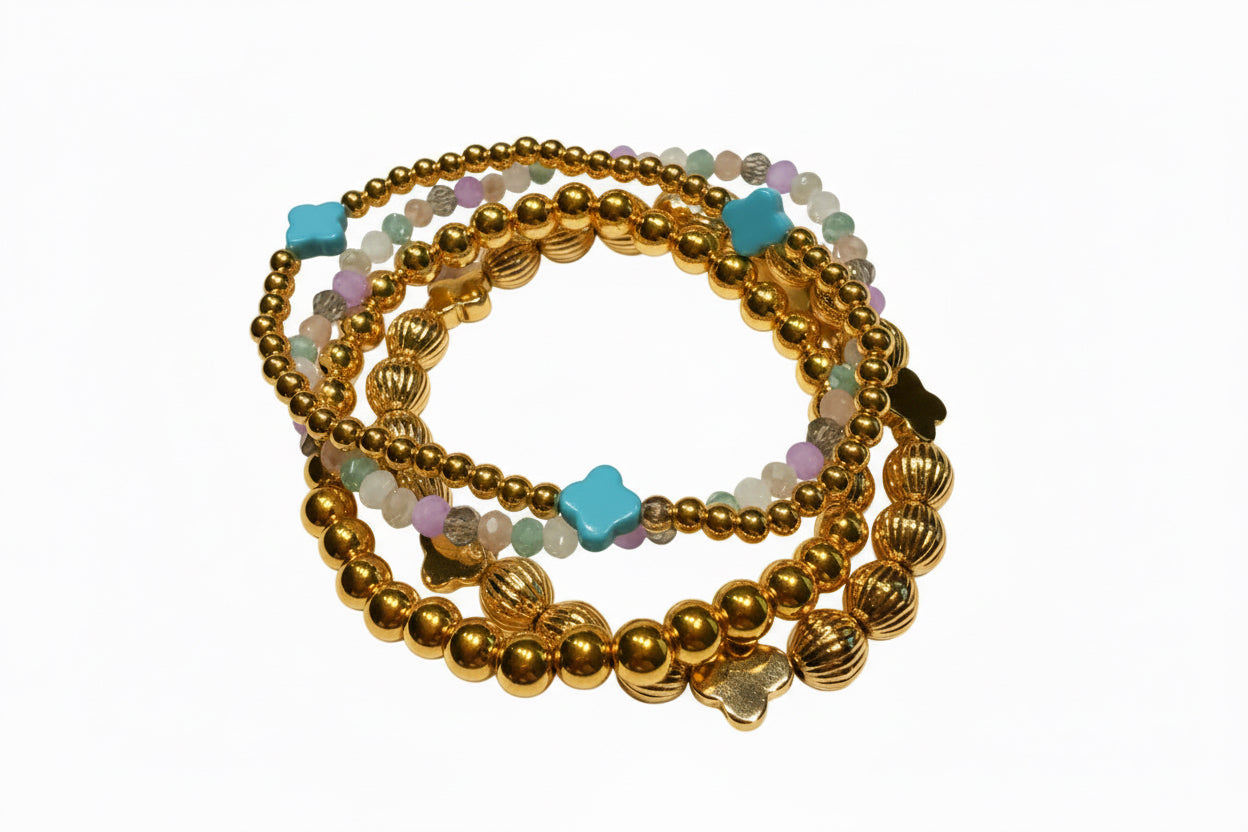 Set of four water-resistant stretch bracelets in gold, white, lavender, and green with turquoise clover charms. Sizes: S/M/L.