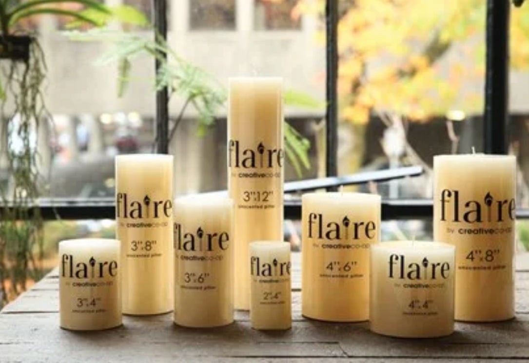 Cream-colored Flaire Unscented Pillar Candles, long-burning, round, available in multiple sizes.