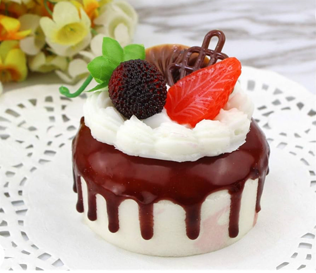 Faux cake with white icing, chocolate glaze drips, candies, red leaf jelly, chocolate curl, green leaves. Sizes: S/M/L.