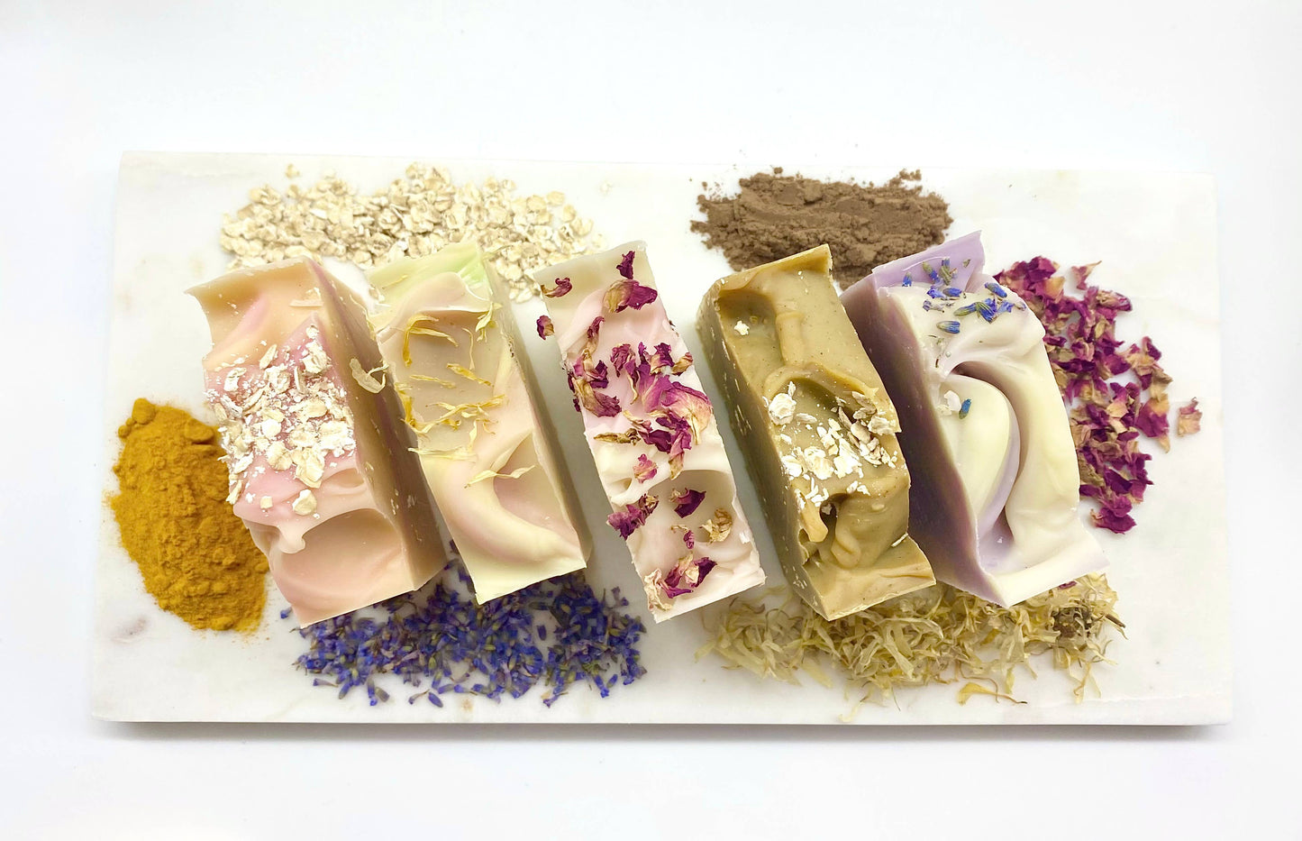 The product is a collection of Lavender Handmade Soap Bars. These VEGAN COLD PROCESS soaps include unique ingredients such as lavender, oats, and spices. Each bar is garnished with colorful botanicals and gold leaf. Sizes available for the product may vary due to its handmade nature.