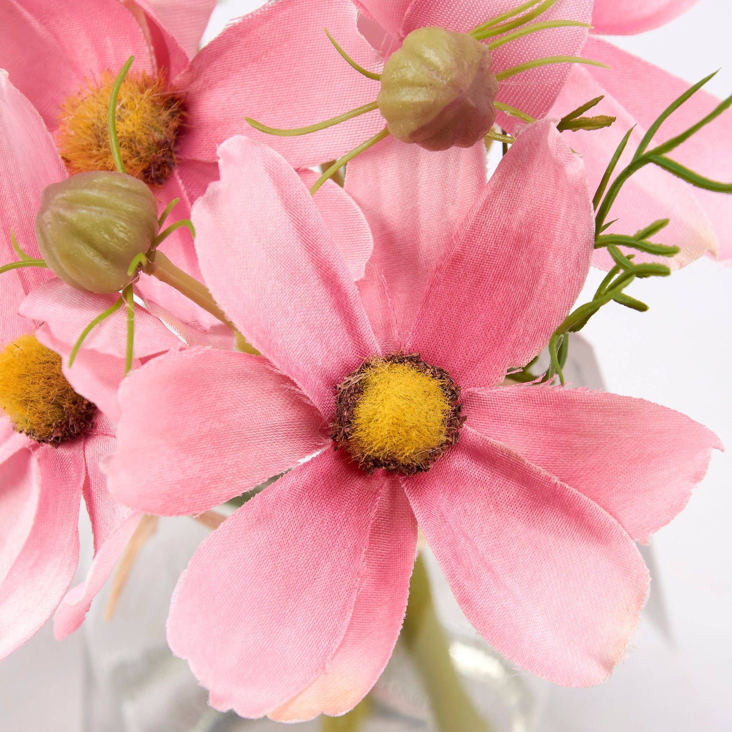 Artificial pink cosmos flowers with yellow centers and green buds in a clear vase. Available in small and medium sizes.