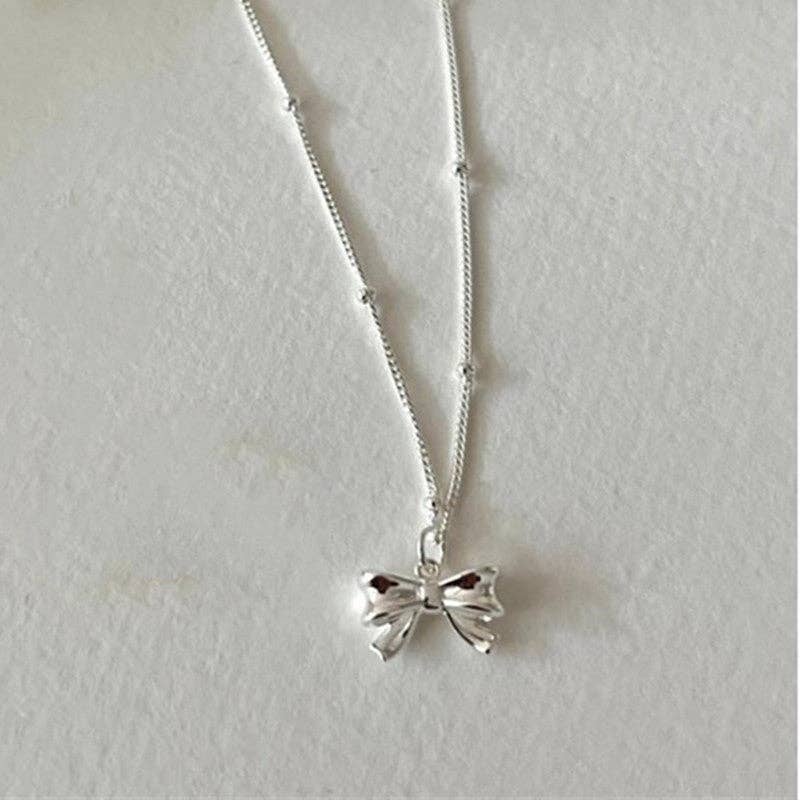 Dainty Bow Tie Bowknot Charm Necklace in 925 Sterling Silver with a shiny bow pendant; available in various sizes.