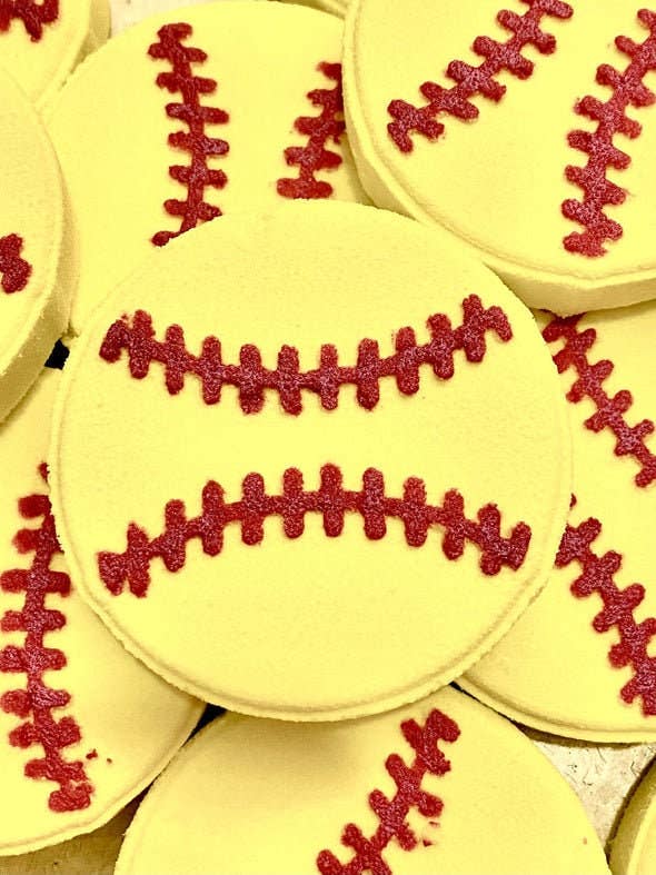 The product is a Baseball Bath Bomb set, styled to resemble white baseballs completed with red stitching. The bath bombs are white and coated with an icing-like decoration. They can come in multiple size options to suit your needs.