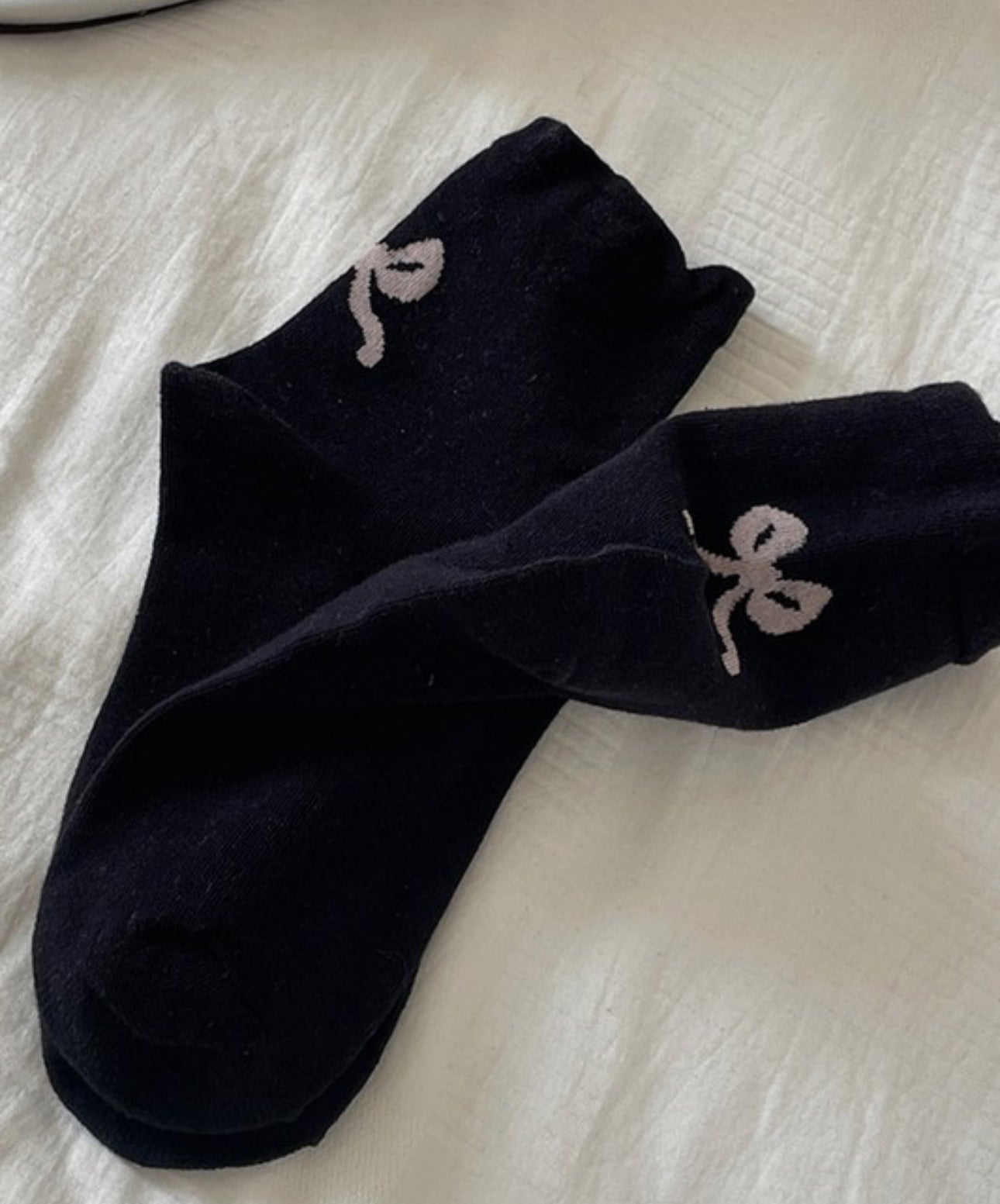 These Bow Mid-Calf Socks are adorned with white embroidery featuring abstract figures. The socks reach up to mid-calf length and have a unique, eye-catching design. They are available in one size that fits all.