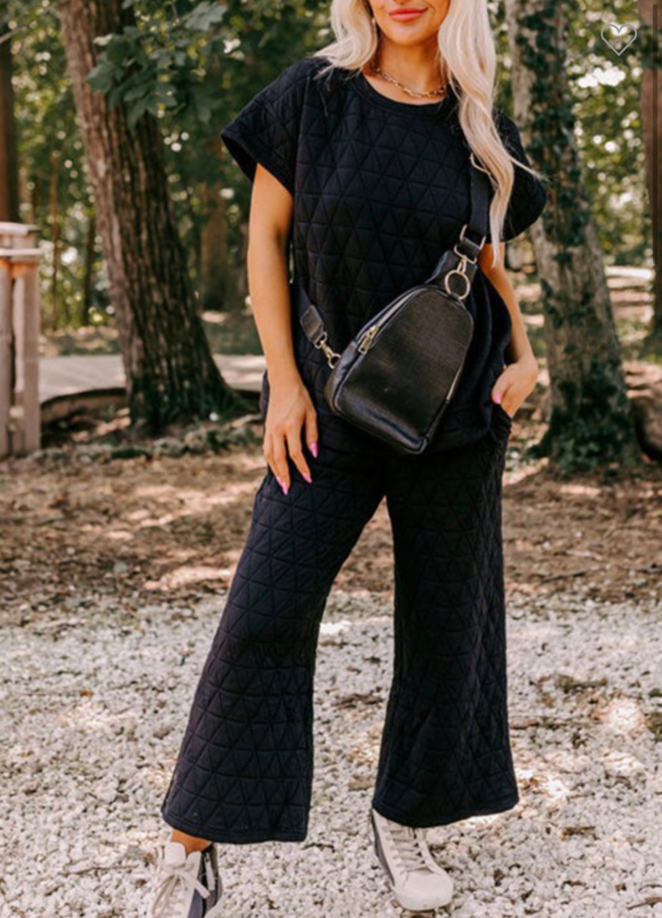 A woman stands outdoors wearing a stylish navy blue Quilted Short Sleeve Wide Leg Pants Set, available in multiple sizing options, with a black crossbody bag and white sneakers.