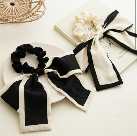 Two elegant Bow Hair Ties featuring long, flowing ribbons in black and white shades. Available in one standard size.