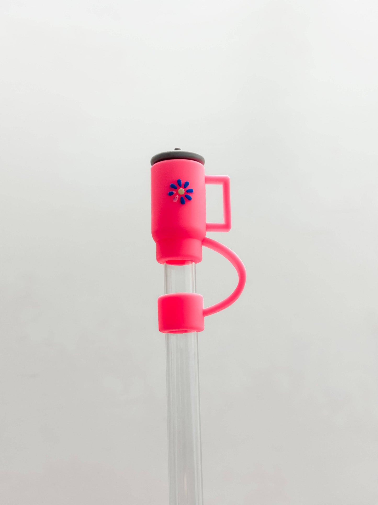 Bright pink silicone straw cover, 10MM size, cup-shaped with flower detail and handle, fits Stanley-size clear straws.