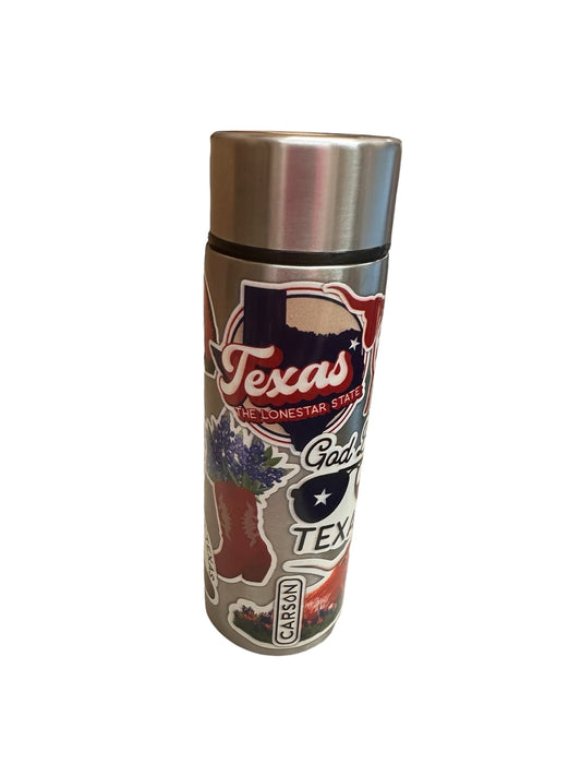 A collection of metal thermoses decorated with Texan designs: the shape of Texas, "The Lone Star State," cowboy boots, bluebonnet flowers, and "God Bless Texas." Available sizes: Tumblers in 12 oz, 20 oz, and 30 oz; Flask decanters in 8 oz.