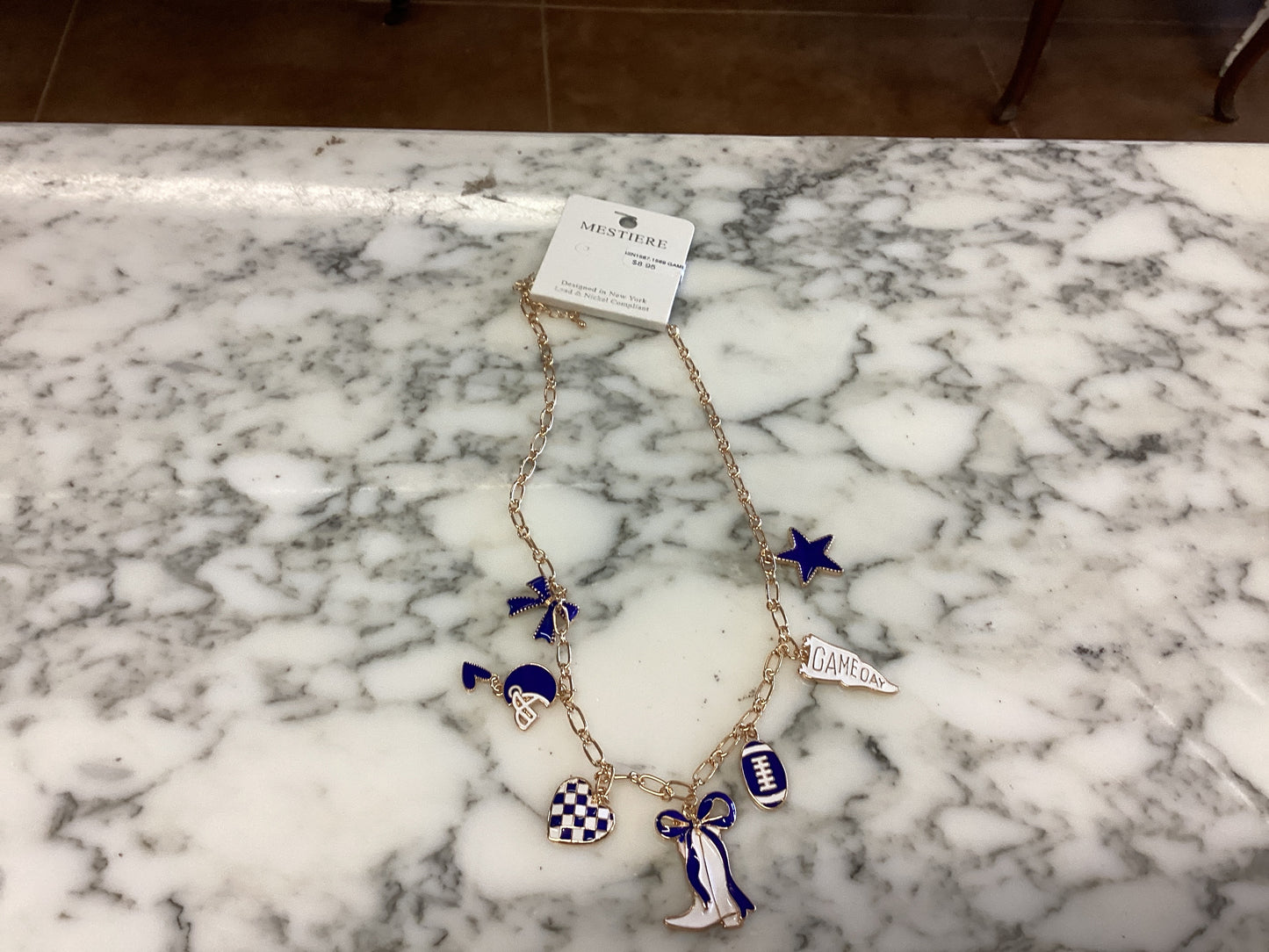 Game Day Necklaces feature a gold chain with blue and white football-themed charms: football, megaphone, star, pennant, and boots. Available in multiple sizes.