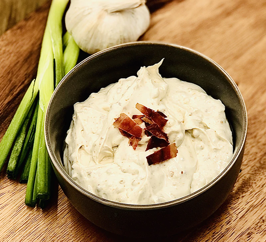Cheddar Bacon Dip Mix in a bowl, topped with crumbled bacon. Available in 8 oz and 16 oz sizes.