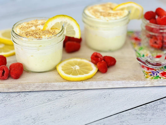 Two small jars of Lemon Ice Box Cheesecake Dip, garnished with lemon slices and crumbs. Available in small size.